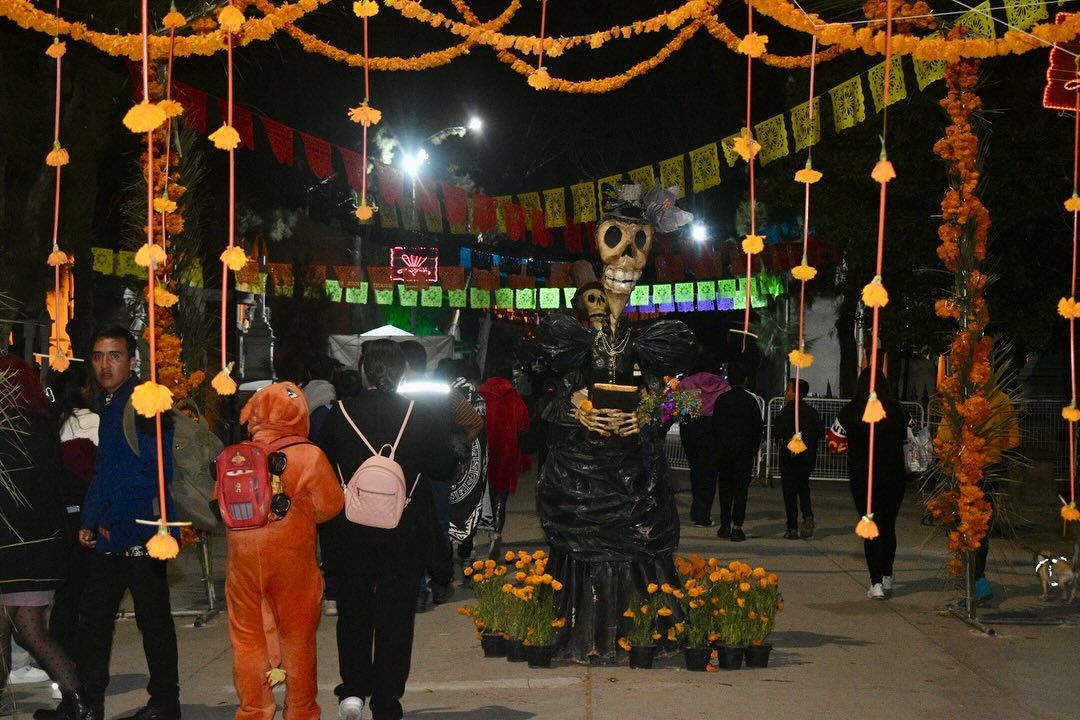 Fotografía de visitantes entrando al panteón El Saucito, de noche