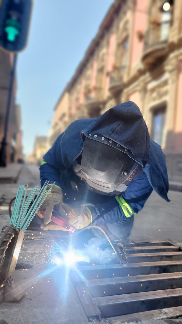 Fotografía de un trabajador municipal soldando una rejilla