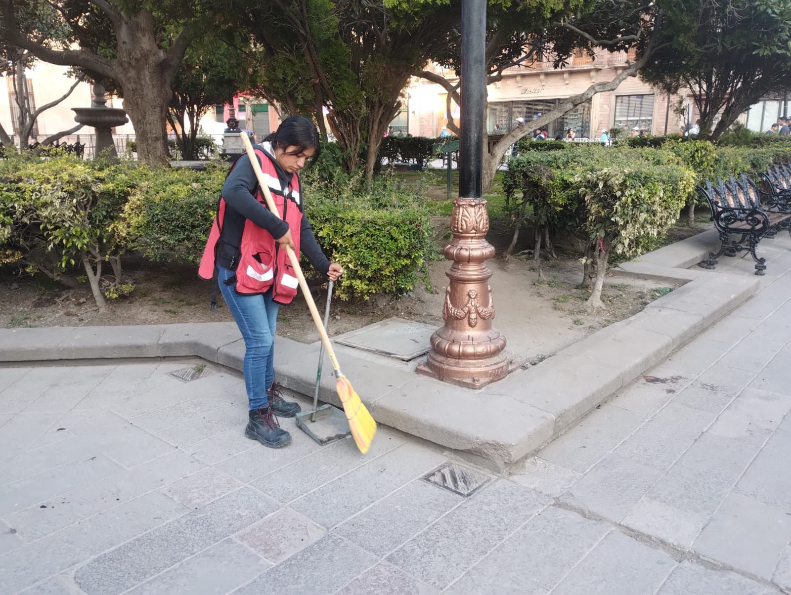 Fotografía de una trabajadora municipal barriendo plaza de armas