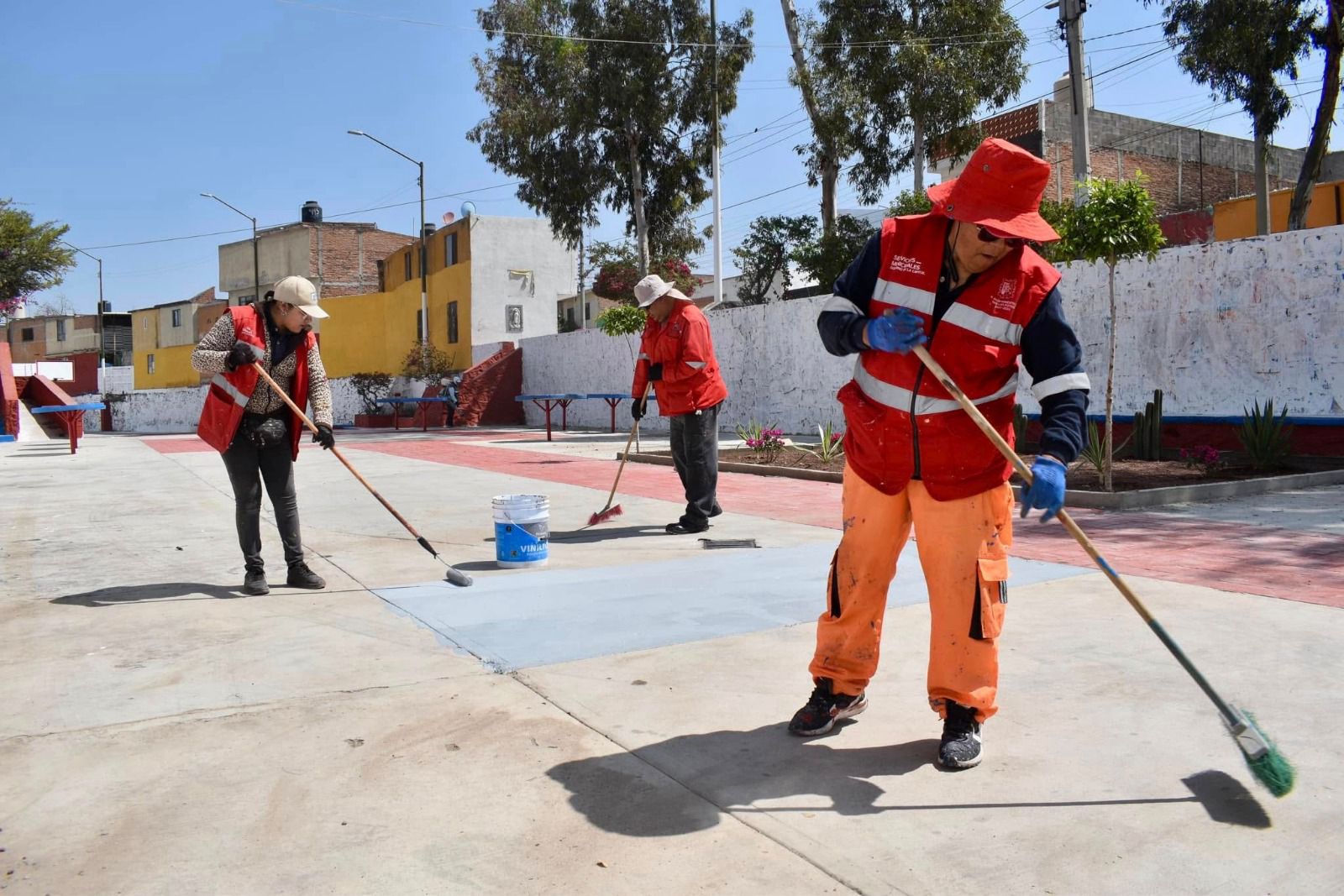 Fotografía de trabajadores municipales barriendo la cancha