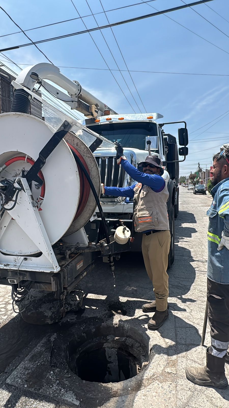 Fotografía de trabajadores desasolvando una alcantarilla