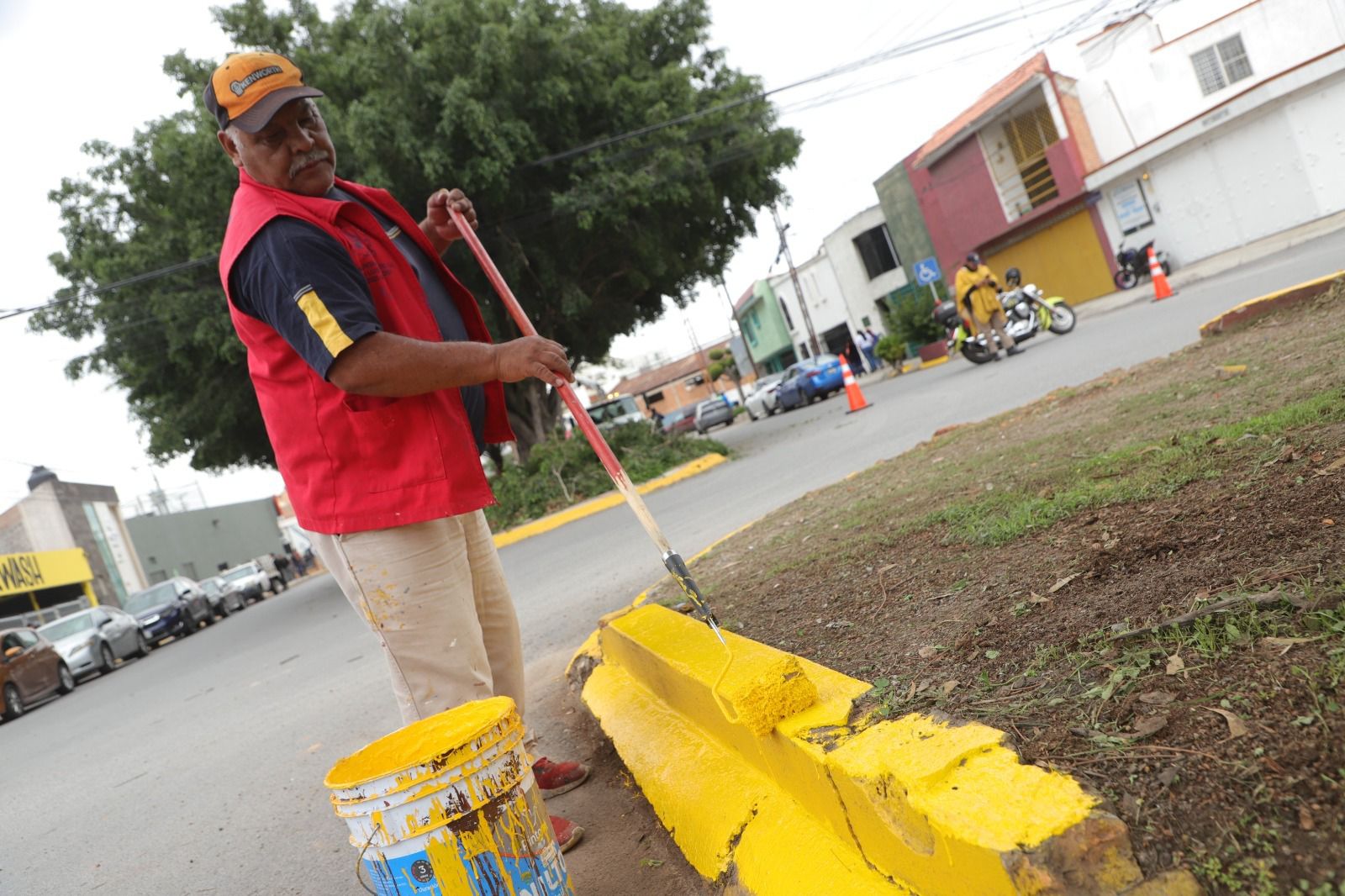 Fotografía de un trabajador municipal pintando la guarnición de una banqueta