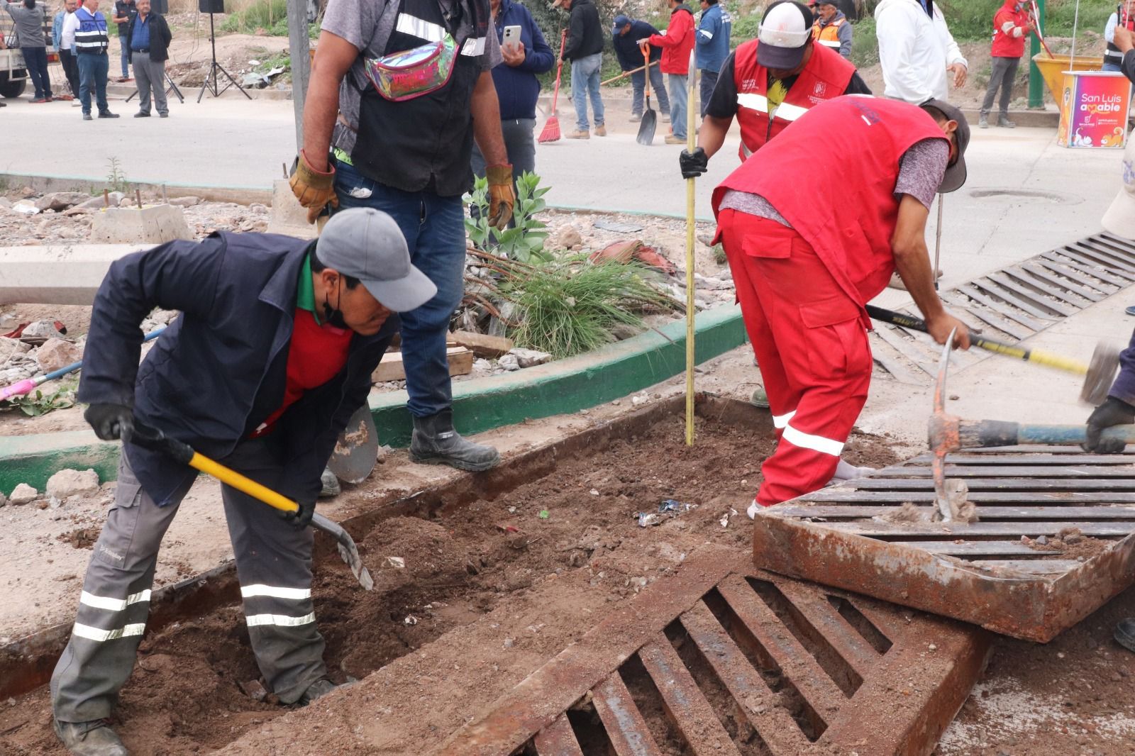 Fotografía de trabajadores municipales limpiando una alcantarilla